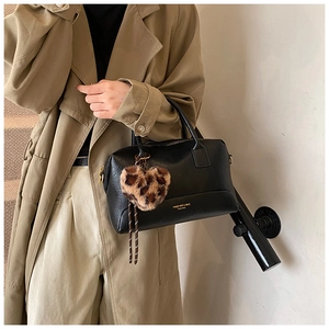 Détail du sac polochon noir avec breloque cœur léopard et garniture dorée sur modèle