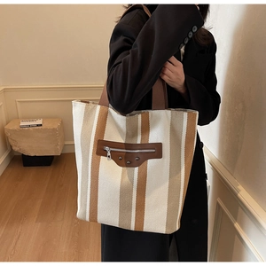 Detail of canvas tote bag with vertical stripes and vintage metal rivet leather patch