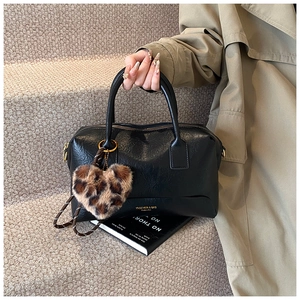 Détail du sac polochon noir avec ferrures dorées et breloque cœur imprimé léopard