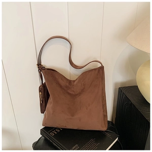 Detail of dark brown suede tote bag with a small matching zip pouch on an art book