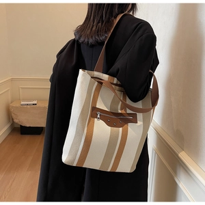 Detailed view of large canvas tote bag with vertical stripes and leather zipper trim