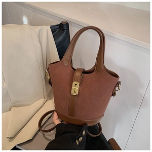 Detail of rust red suede bucket bag with brown leather trim and golden metal clasp