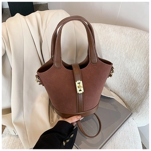 Detailed view of brown suede bucket bag with gold clasp on an elegant chair