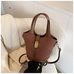 Detail of dark brown suede bucket bag with gold metallic buckle on a beige blazer background