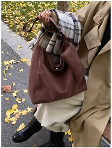Deep brown matte suede tote bag shown on shoulder in autumn street style setting