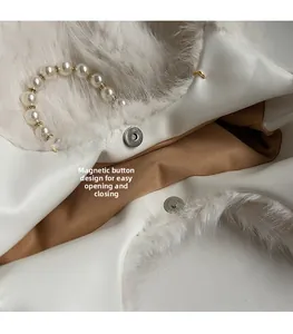 Detail of white faux fur bag showing the magnetic buckle and luxury pearl handle