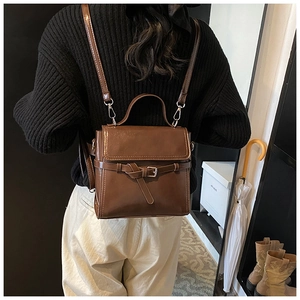 Modell trägt dunkelbraunen Vintage-Rucksack aus Kunstleder mit Metallschnallenverschluss