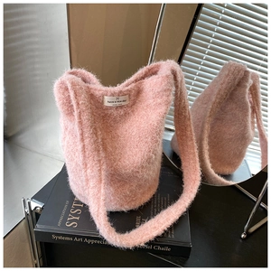 Détail du sac seau en peluche rose avec étiquette tissée et bandoulière large douce