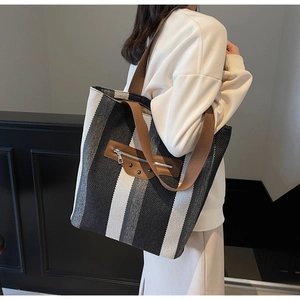 Detail of striped canvas tote with brown leather zipper pocket and rivet accents
