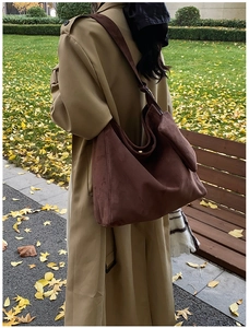 Close-up of large brown frosted leather tote bag worn with a khaki trench coat