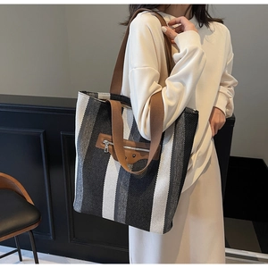 Detailed shot of large striped canvas tote bag with brown woven straps on a model