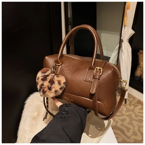Détail du sac polochon en cuir marron vintage avec un pendentif cœur léopard chic