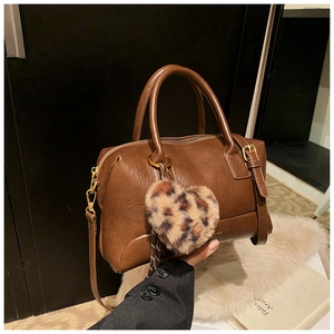 Détail du sac boston marron foncé en similicuir avec breloque cœur léopard et garnitures