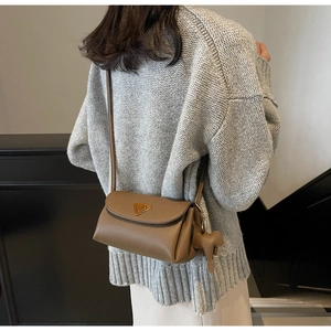 Brown litchi leather crossbody bag with triangular metal logo and elephant charm accessory