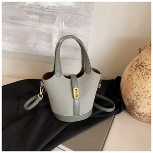 Detailed macro view of gray-green matte bucket bag with gold lock and adjustable strap
