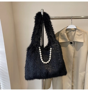 Detail of black faux fur tote bag with pearl chain decoration and wide shoulder strap