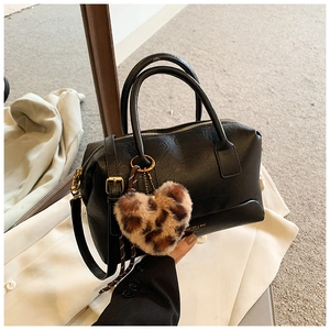 Détail du sac polochon noir en similicuir avec lettrage doré et breloque cœur léopard