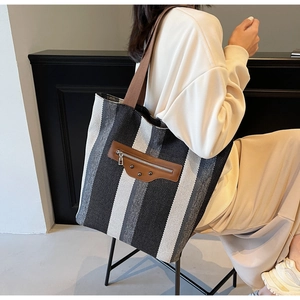 Detail of striped canvas tote bag with leather zipper pocket and vintage metal rivets