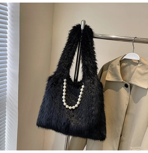 Detailed close-up of a black faux fur handbag featuring elegant white pearl chain decoration