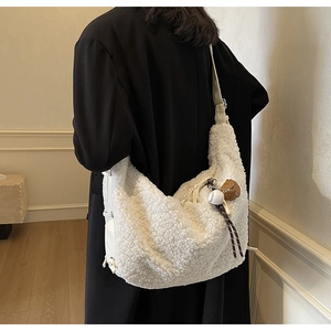 Detail of white plush dumpling bag with unique mini baseball and glove charms for winter