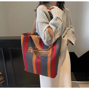 Detail of colorful striped canvas tote bag showing wide strap and leather zipper pocket