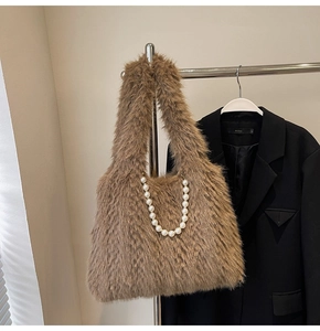 Detail of light brown plush handbag featuring decorative large white pearl chain