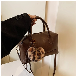 Détail de sac Boston marron foncé avec un pendentif en forme de cœur léopard