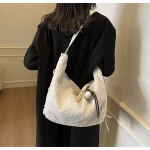 Close-up of white wool crossbody bag with a baseball charm shown on model back