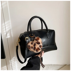 Détail d'un sac oreiller en cuir noir avec ferrures dorées et breloque cœur léopard