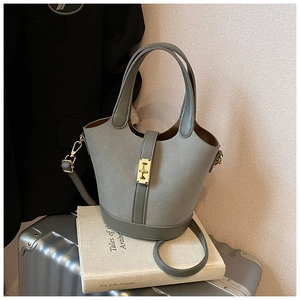 Detail view of grey suede bucket bag with gold hardware and smooth leather base
