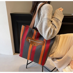 Detail of colorful striped canvas tote bag showing the leather zipper pocket and studs