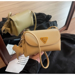 Detail of yellow lychee leather bag with metal triangle plaque and elephant charm