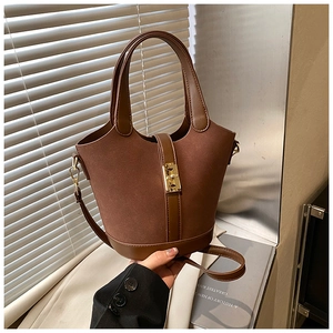 Close-up of vintage brown suede bucket bag featuring a gold hardware lock and dual textures