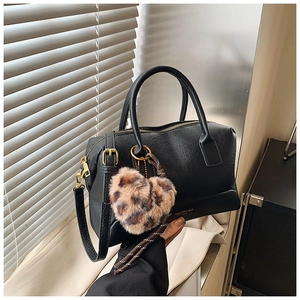 Détail d'un sac Boston noir en similicuir avec un charm cœur en peluche à motif léopard