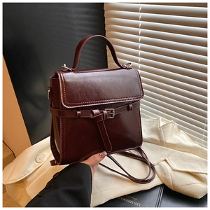 Nahaufnahme der dunkel weinroten Vintage-Handtasche mit Metallschnalle und glänzendem Leder