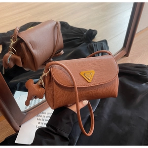 Detail of brown litchi pattern leather bag featuring gold logo and cute elephant charm