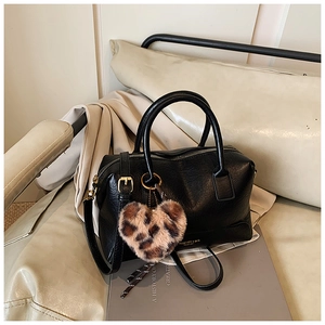 Détail du sac oreiller en cuir noir avec ferrures dorées et breloque cœur léopard