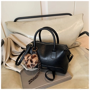 Détail du sac polochon en cuir noir avec breloque cœur léopard et lettrage doré