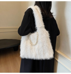 Detail of white faux fur shoulder bag featuring a decorative pearl chain on a model