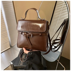 Detail eines dunkelbraunen Rucksacks aus poliertem Leder mit Metallschnalle und Tragegriff