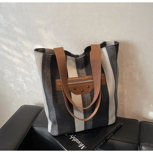 Detail of striped canvas tote with vintage rivets and front zipper pocket on leather bench