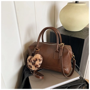 Vue détaillée d'un sac Boston vintage marron avec charm cœur léopard et bandoulière
