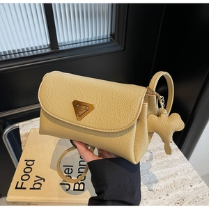 Detail of light yellow lychee pattern leather bag with gold triangular metal logo