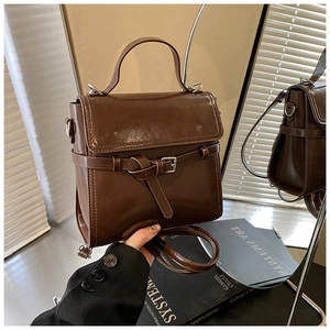Detail einer Vintage dunkelbraunen Lederhandtasche mit Riemenschnalle und Metallringen