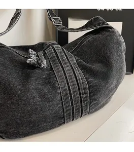 Detail of vintage washed denim hobo bag featuring frayed edges and adjustable strap
