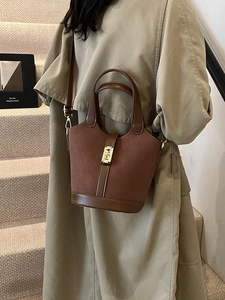 Retro brown suede bucket bag with gold rabbit buckle worn by model in beige trench coat