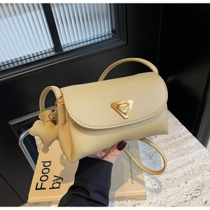 Detailed close-up of beige lychee leather bag with gold triangle logo and animal charm