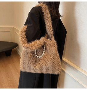 Detail of brown faux fur shoulder bag with pearl chain decoration on black wool coat