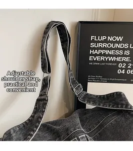 Detail of adjustable wide shoulder strap with silver metal buckle on washed denim bag