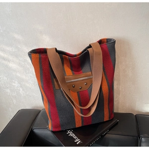 Detail of canvas tote bag with striped pattern and vintage leather zipper patch with studs